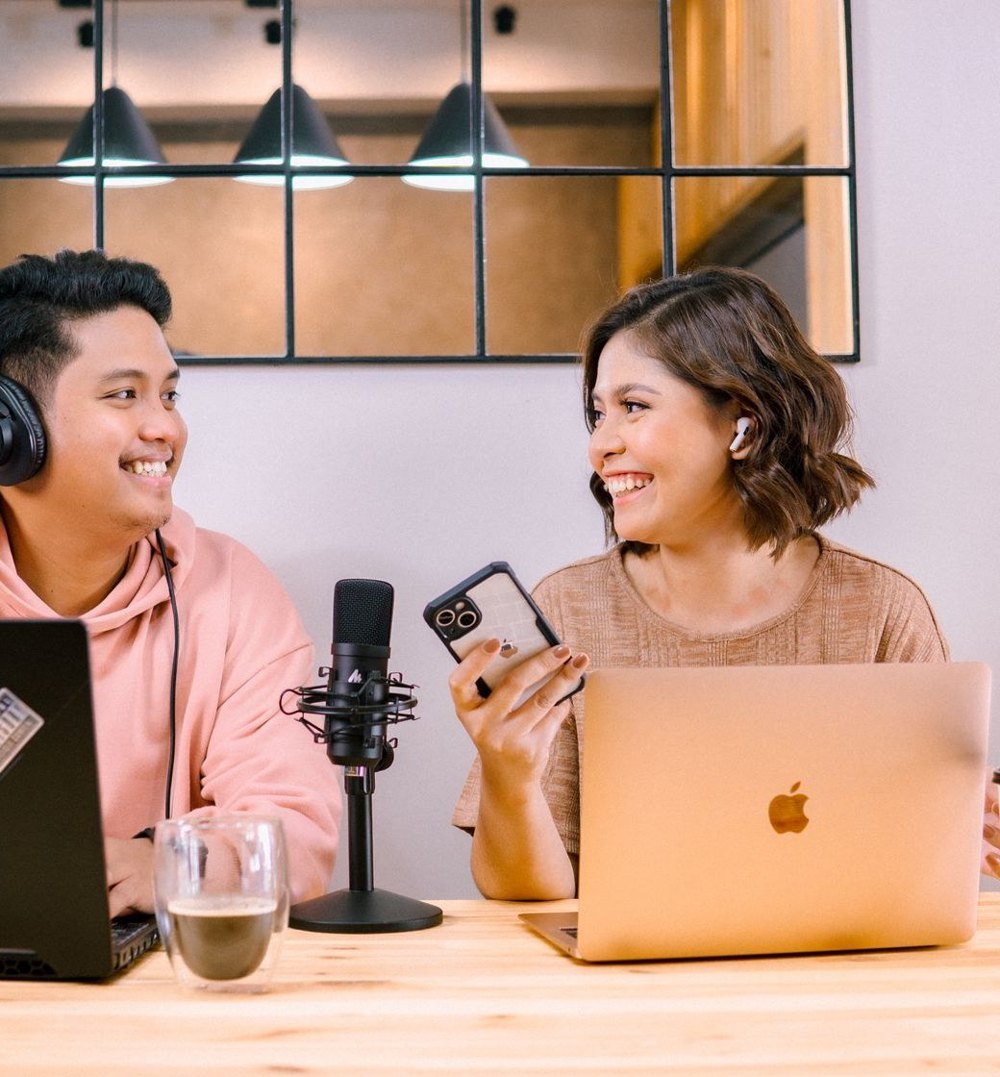 Two colleagues smiling at each other while working at laptops