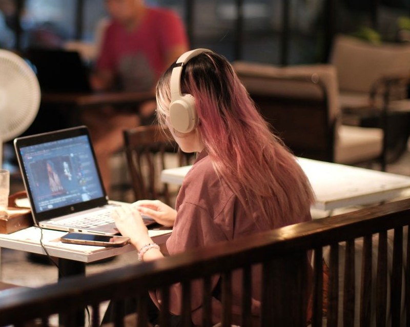 Woman wearing headphones working on a laptop